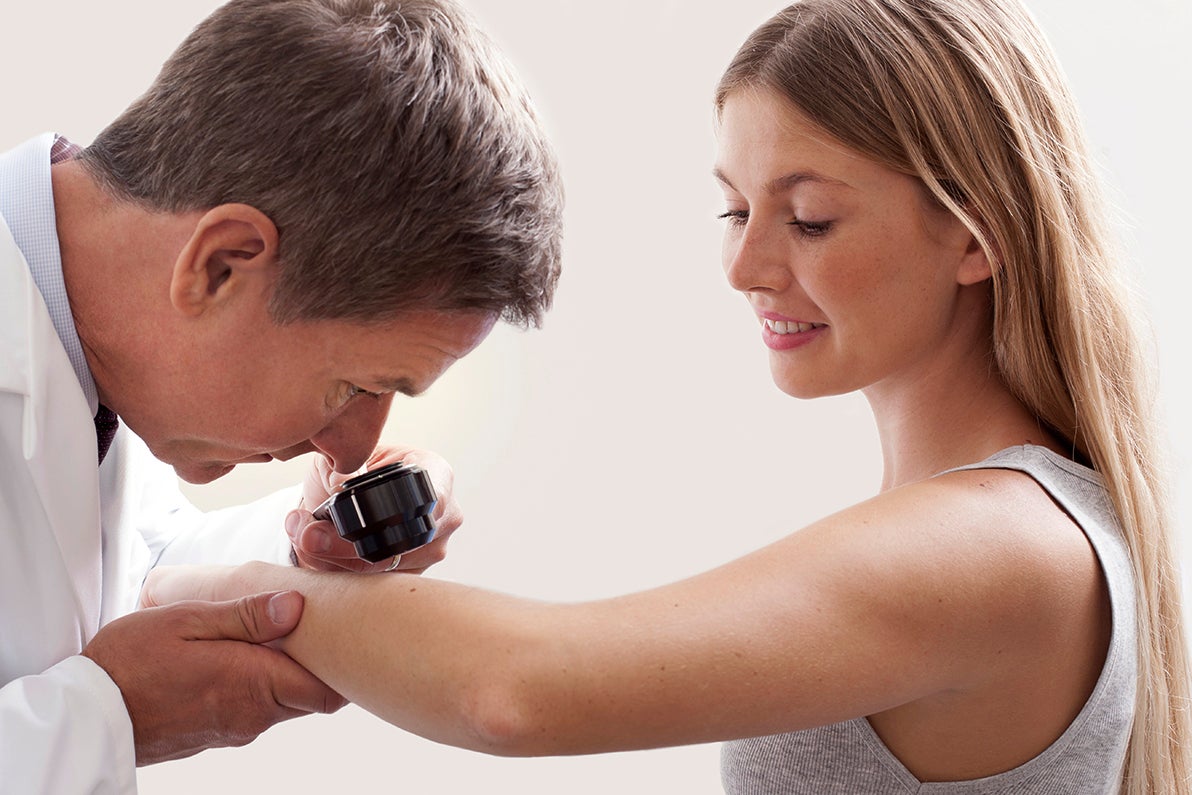 Male doctor checking skin of female patient with scope
